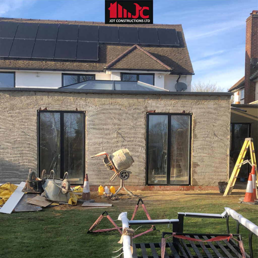 Home extension construction in progress with rendering and sliding doors by JOT Constructions Ltd